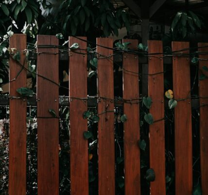 Close-up view of a wooden fence with vines and greenery